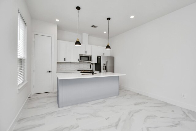 849 Mansfield St Unit A, Houston, TX 77091 - kitchen with stainless steel appliances, white cabinets, decorative backsplash, a kitchen island with sink, and plenty of natural light