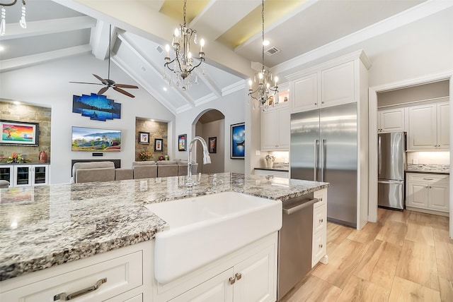 22414 Meadowhurst Cir W, Tomball, TX 77377 - kitchen featuring appliances with stainless steel finishes, arched walkways, a sink, ceiling fan, and light stone countertops