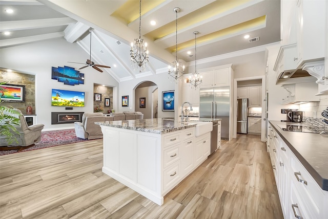 22414 Meadowhurst Cir W, Tomball, TX 77377 - kitchen featuring a sink, beam ceiling, arched walkways, light wood finished floors, and freestanding refrigerator
