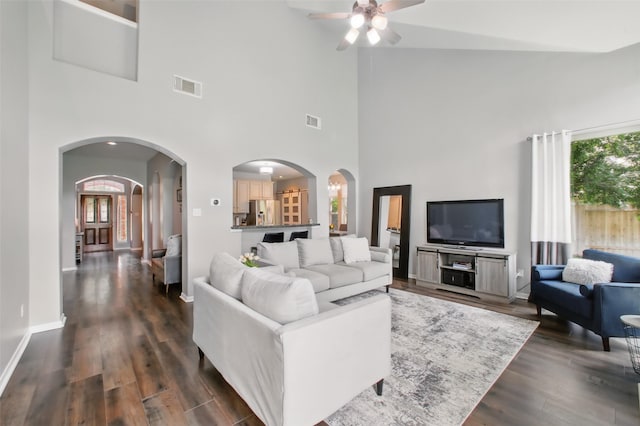 9103 Huckinston Ct, Spring, TX 77379 - living area featuring arched walkways, a ceiling fan, dark wood-type flooring, a high ceiling, and baseboards