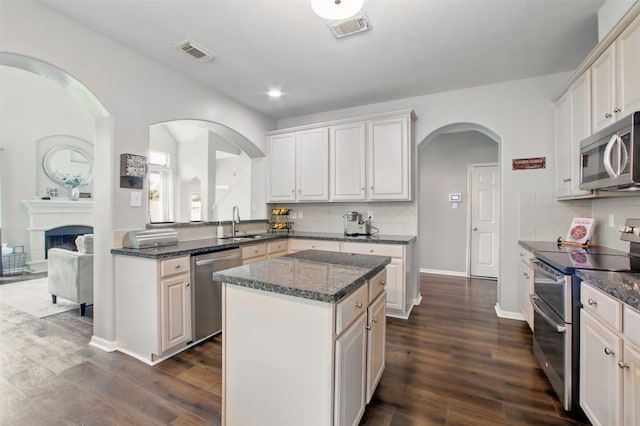9103 Huckinston Ct, Spring, TX 77379 - kitchen with stainless steel appliances, a kitchen island, a sink, dark wood-style flooring, and recessed lighting