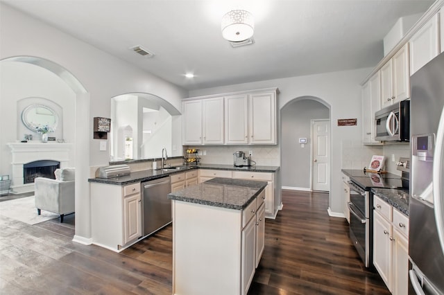 9103 Huckinston Ct, Spring, TX 77379 - kitchen with appliances with stainless steel finishes, a sink, arched walkways, a center island, and dark wood-type flooring