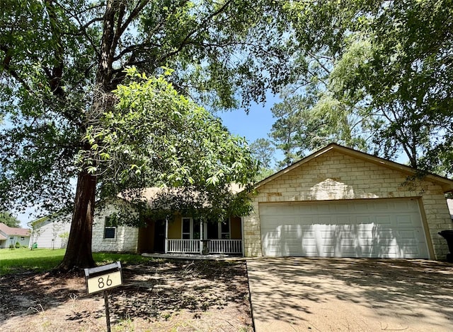 86 Huntington, Trinity, TX 75862 - view of front of home featuring driveway, an attached garage, stone siding, and a porch