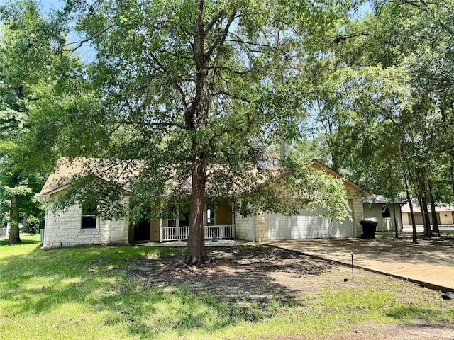 86 Huntington, Trinity, TX 75862 - view of front facade featuring covered porch, concrete driveway, an attached garage, and a front lawn