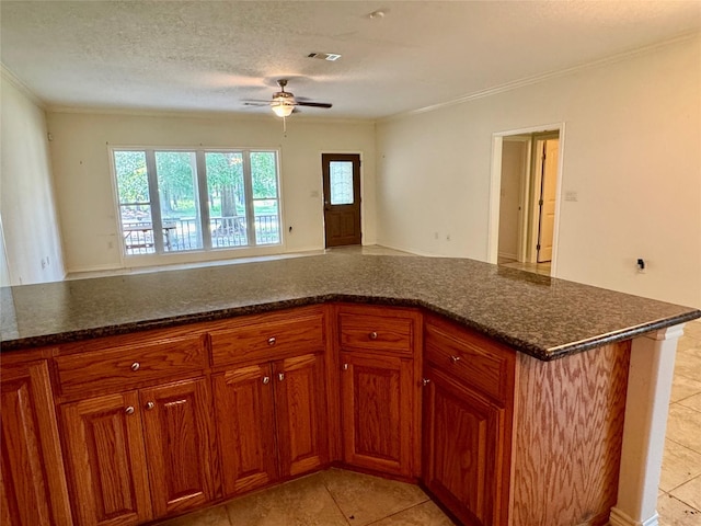 86 Huntington, Trinity, TX 75862 - kitchen with ceiling fan, crown molding, brown cabinets, light tile patterned floors, and dark stone countertops