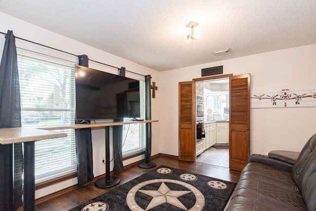 12210 Rocky Lake Ct, Houston, TX 77070 - living room featuring wood finished floors, healthy amount of natural light, a textured ceiling, and baseboards
