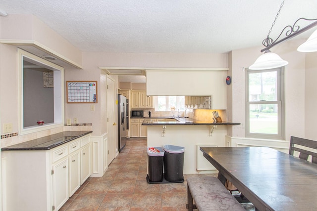 12210 Rocky Lake Ct, Houston, TX 77070 - kitchen featuring stainless steel refrigerator with ice dispenser, a peninsula, black microwave, dark countertops, and a textured ceiling