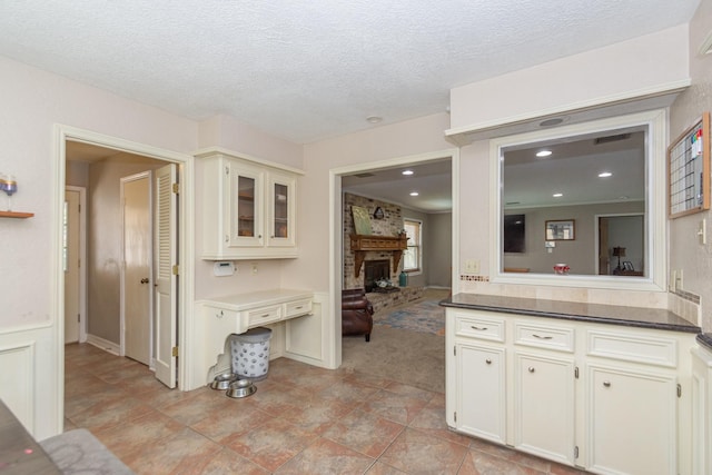 12210 Rocky Lake Ct, Houston, TX 77070 - kitchen featuring light colored carpet, glass insert cabinets, a textured ceiling, and a brick fireplace