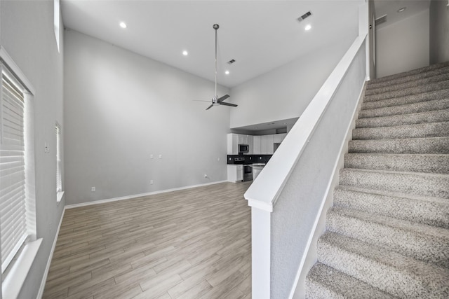 4006 Frontier Rd, Willis, TX 77378 - stairs with a towering ceiling, a ceiling fan, wood finished floors, recessed lighting, and baseboards