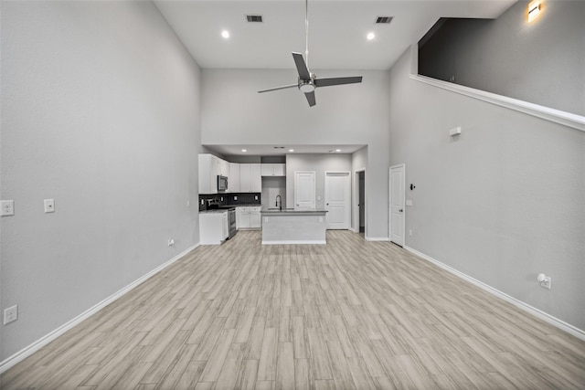 4006 Frontier Rd, Willis, TX 77378 - unfurnished living room featuring ceiling fan, high vaulted ceiling, baseboards, a sink, and light wood finished floors