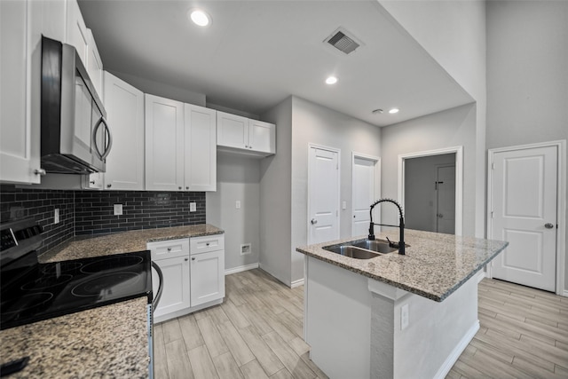 4006 Frontier Rd, Willis, TX 77378 - kitchen with stainless steel microwave, a sink, range with electric cooktop, baseboards, and white cabinets