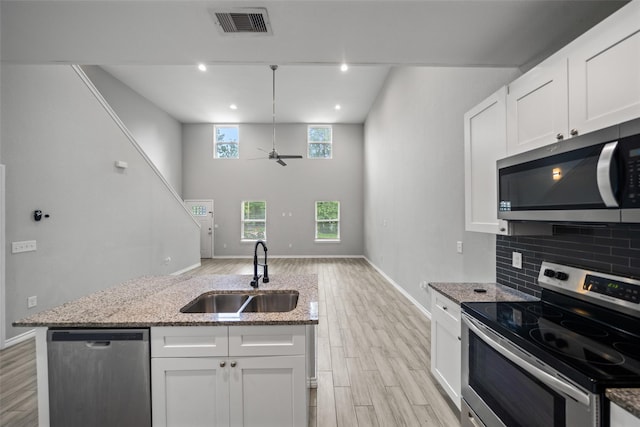 4006 Frontier Rd, Willis, TX 77378 - kitchen featuring appliances with stainless steel finishes, a sink, a ceiling fan, light wood-style floors, and a high ceiling