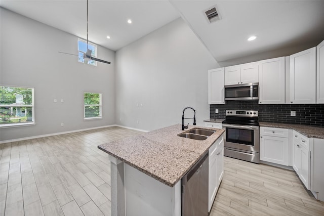 4006 Frontier Rd, Willis, TX 77378 - kitchen with stainless steel appliances, a sink, high vaulted ceiling, light stone countertops, and tasteful backsplash