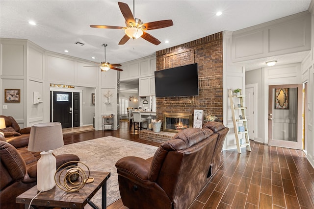 2205 Erin Glen Ct, Deer Park, TX 77536 - living room featuring a decorative wall, ceiling fan, recessed lighting, a fireplace, and dark wood-style floors