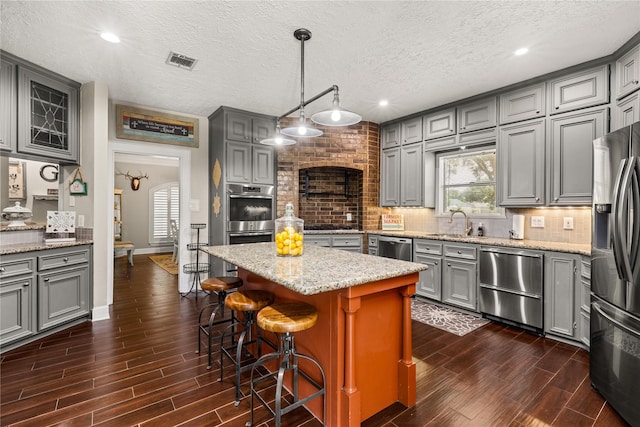 2205 Erin Glen Ct, Deer Park, TX 77536 - kitchen featuring gray cabinets, appliances with stainless steel finishes, dark wood finished floors, backsplash, and a kitchen island