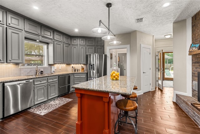 2205 Erin Glen Ct, Deer Park, TX 77536 - kitchen with stainless steel appliances, dark wood-style floors, gray cabinets, a kitchen island, and tasteful backsplash