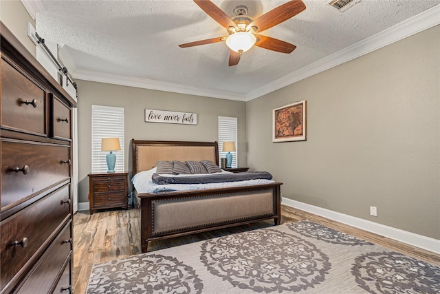 2205 Erin Glen Ct, Deer Park, TX 77536 - bedroom with a textured ceiling, baseboards, light wood-style flooring, ornamental molding, and a ceiling fan