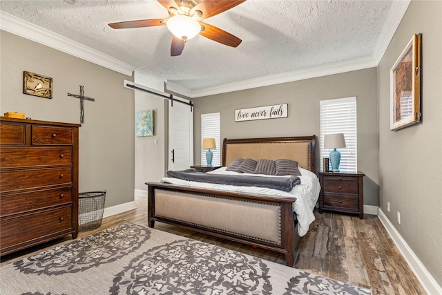 2205 Erin Glen Ct, Deer Park, TX 77536 - bedroom featuring a textured ceiling, a barn door, ornamental molding, wood finished floors, and baseboards