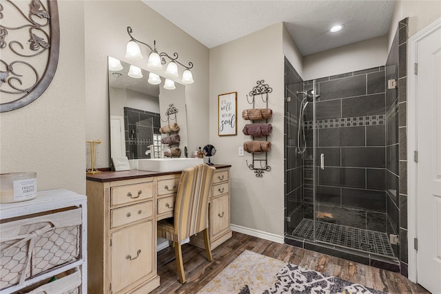 2205 Erin Glen Ct, Deer Park, TX 77536 - bathroom featuring wood finished floors, a stall shower, vanity, baseboards, and a textured ceiling