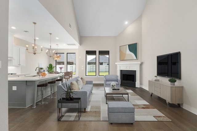 5115 Prairie Gourd Mdw, Manvel, TX 77578 - living area with a chandelier, dark wood-style flooring, a towering ceiling, a fireplace with flush hearth, and recessed lighting