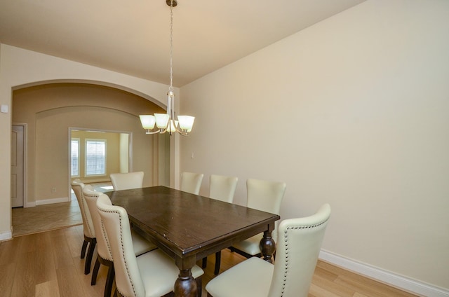13806 Crystal Harbor Ln, Pearland, TX 77584 - dining room featuring light wood finished floors, a chandelier, baseboards, and arched walkways