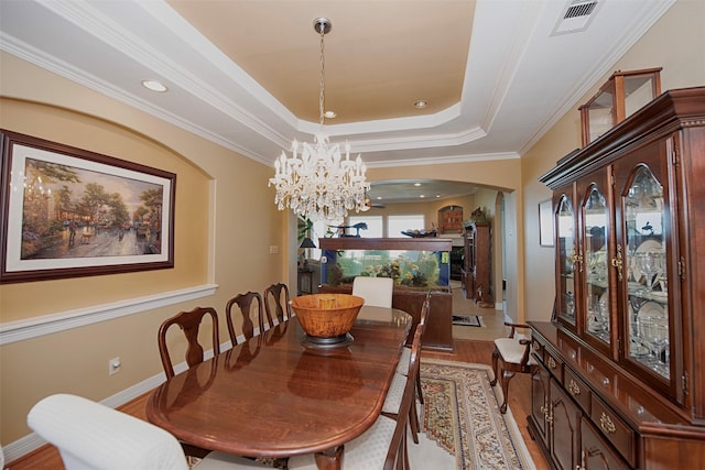 2242 Marina Way, League City, TX 77565 - dining space featuring arched walkways, a chandelier, light wood-style floors, crown molding, and a raised ceiling