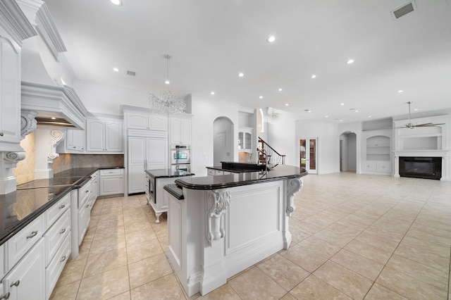 169 Westlake Pt, Montgomery, TX 77356 - kitchen with ceiling fan, arched walkways, light tile patterned flooring, a spacious island, and backsplash