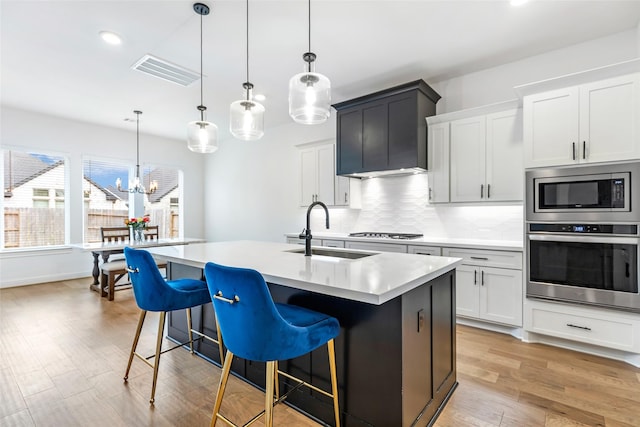 11914 Parsifal Creek Rd, Humble, TX 77346 - kitchen with appliances with stainless steel finishes, a sink, light countertops, decorative backsplash, and light wood-style flooring
