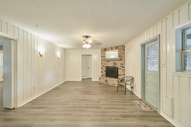 1103 Hillcrest Dr, Conroe, TX 77301 - unfurnished living room featuring ceiling fan, a brick fireplace, and light wood-style flooring