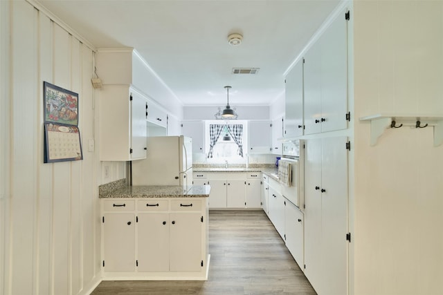 1103 Hillcrest Dr, Conroe, TX 77301 - kitchen with white appliances, light wood-style flooring, a sink, a peninsula, and hanging light fixtures