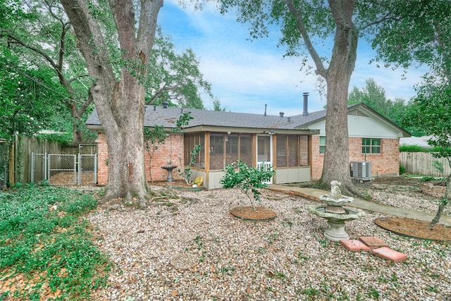 1103 Hillcrest Dr, Conroe, TX 77301 - back of property with a sunroom, brick siding, central air condition unit, and roof with shingles