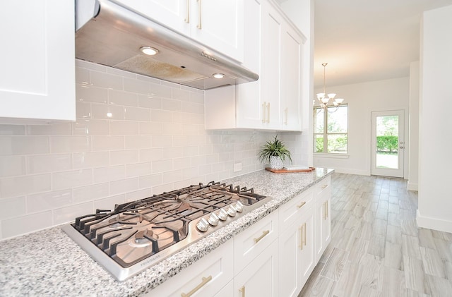 810 Sunbeam Creek Ct, Richmond, TX 77406 - kitchen with stainless steel gas stovetop, under cabinet range hood, decorative backsplash, white cabinets, and baseboards
