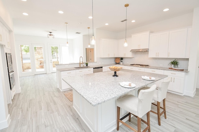 810 Sunbeam Creek Ct, Richmond, TX 77406 - kitchen featuring a peninsula, stainless steel appliances, under cabinet range hood, a sink, and white cabinetry