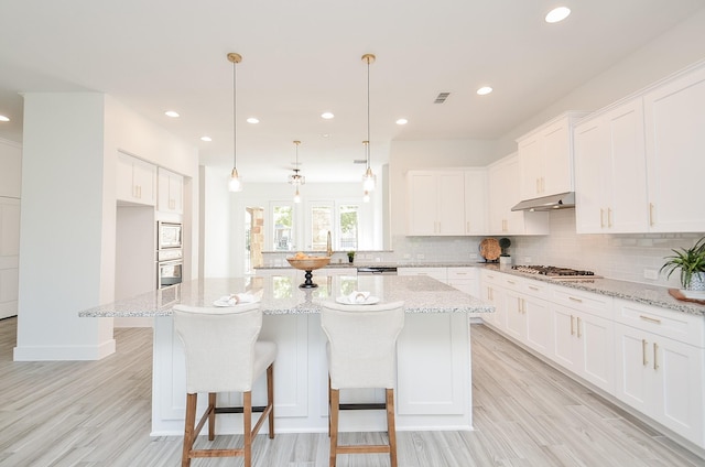 810 Sunbeam Creek Ct, Richmond, TX 77406 - kitchen featuring under cabinet range hood, decorative backsplash, recessed lighting, white cabinets, and light wood finished floors