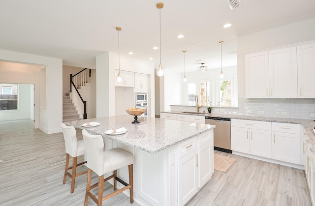 810 Sunbeam Creek Ct, Richmond, TX 77406 - kitchen featuring stainless steel appliances, a sink, a kitchen island, white cabinets, and recessed lighting
