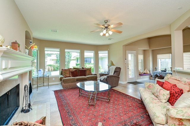 5703 Bent Arbor Ln, Katy, TX 77450 - living room featuring arched walkways, a fireplace, ceiling fan, light tile patterned floors, and baseboards