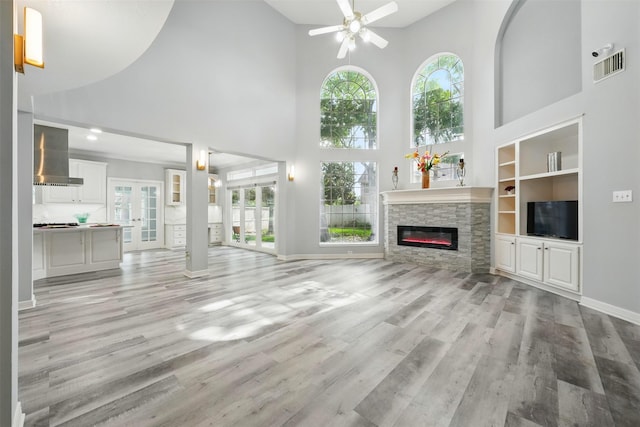 2003 Birnam Wood Dr, Sugar Land, TX 77479 - unfurnished living room featuring a high ceiling, ceiling fan, light wood-style floors, a fireplace, and baseboards