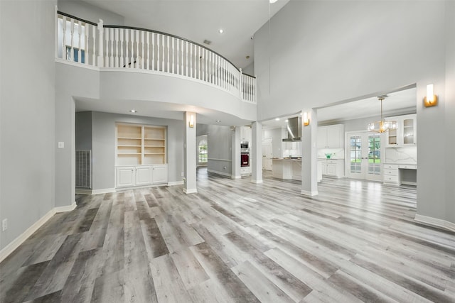 2003 Birnam Wood Dr, Sugar Land, TX 77479 - unfurnished living room featuring light wood-type flooring, healthy amount of natural light, a high ceiling, a chandelier, and baseboards