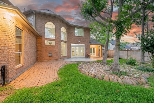 2003 Birnam Wood Dr, Sugar Land, TX 77479 - back of property at dusk with a patio, french doors, brick siding, and a shingled roof
