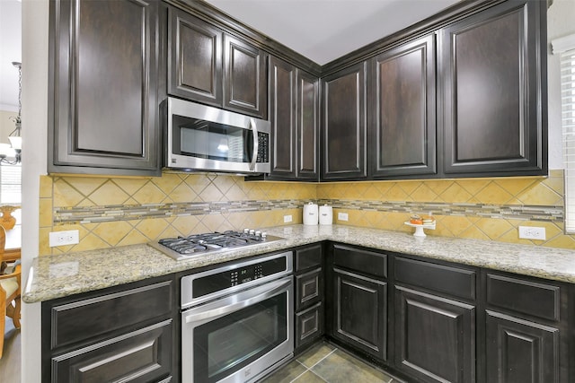139 S Ridge Park Dr, Magnolia, TX 77354 - kitchen with stainless steel appliances, tasteful backsplash, light stone counters, and dark brown cabinets