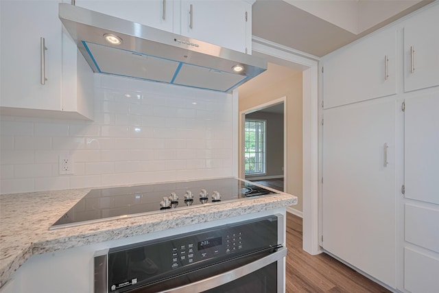 1316 Courtney St, Richmond, TX 77469 - kitchen featuring extractor fan, wall oven, wood finished floors, tasteful backsplash, and white cabinetry