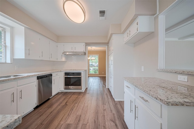 1316 Courtney St, Richmond, TX 77469 - kitchen featuring appliances with stainless steel finishes, under cabinet range hood, wood finished floors, white cabinets, and backsplash