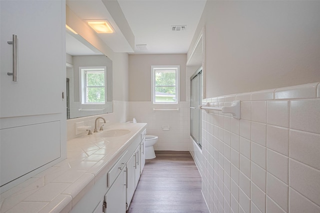 1316 Courtney St, Richmond, TX 77469 - bathroom featuring toilet, double vanity, tile walls, wood finished floors, and wainscoting