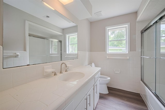 1316 Courtney St, Richmond, TX 77469 - full bathroom with tile walls, plenty of natural light, vanity, toilet, and wood finished floors