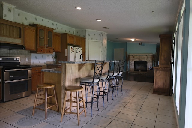 10912 Fm 523rd Rd, Angleton, TX 77515 - kitchen with range with two ovens, freestanding refrigerator, range hood, a textured ceiling, and a breakfast bar area