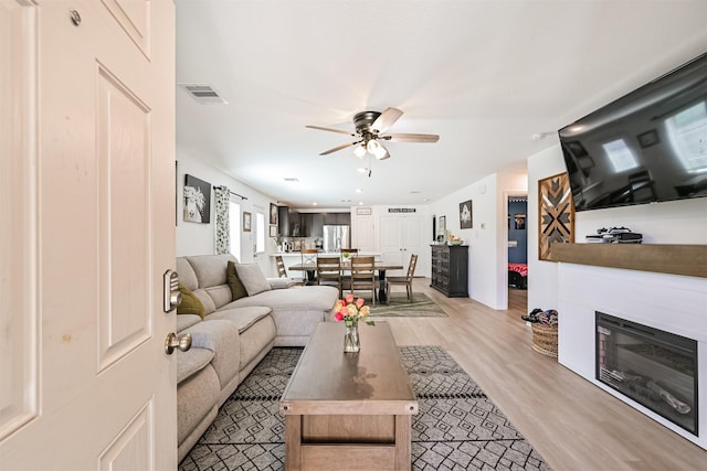 138 Austin Rd, Angleton, TX 77515 - living area featuring ceiling fan, light wood-style flooring, and a glass covered fireplace