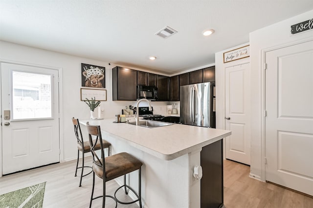 138 Austin Rd, Angleton, TX 77515 - kitchen with freestanding refrigerator, black microwave, a breakfast bar, light wood-type flooring, and dark brown cabinets