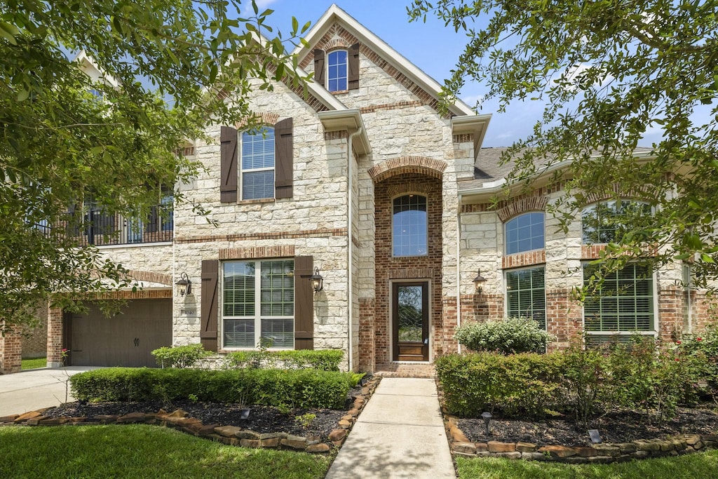 1040 Bolivar Point Ln, Friendswood, TX 77546 - french country style house with an attached garage, driveway, and stone siding