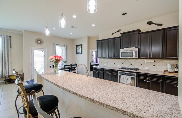 4419 Rolling Field Ln, Sugar Land, TX 77479 - kitchen with stainless steel appliances, backsplash, a breakfast bar, decorative light fixtures, and light stone countertops