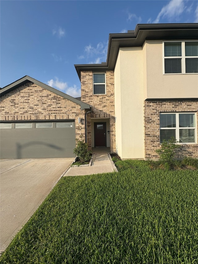29506 Wilkerson Ln, Katy, TX 77494 - view of front of property with brick siding, an attached garage, stucco siding, concrete driveway, and a front lawn